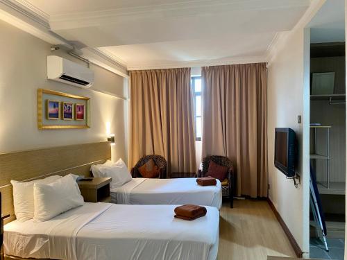 a hotel room with two beds and a television at Sumai Hotel Apartment in Kuala Terengganu