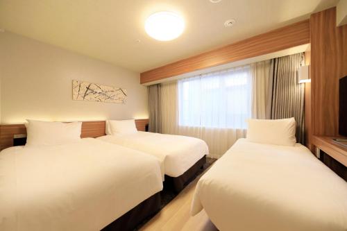 a hotel room with two beds and a window at Richmond Hotel Nagoya Shinkansen-guchi in Nagoya
