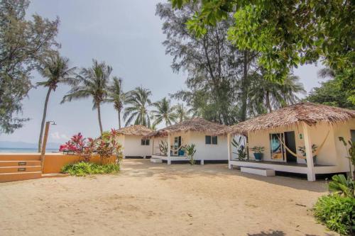 a row of cottages on the beach with palm trees at Sarana Bungalows in Baan Tai