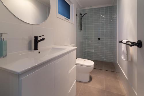 a white bathroom with a sink and a toilet at Poinciana at Cooee Bay in Yeppoon