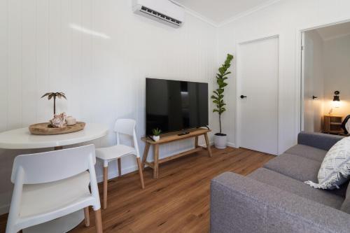 a living room with a couch and a table and a tv at Poinciana at Cooee Bay in Yeppoon