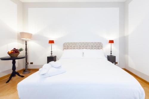 a bedroom with a large white bed with two lamps at Salotto Monti in Rome