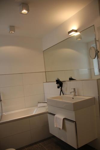 a bathroom with a sink and a mirror and a tub at Hotel Restaurant Schwan in Wertheim