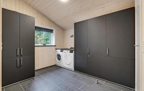a laundry room with black cabinets and a washing machine at Awesome Home In Blåvand With Sauna in Blåvand