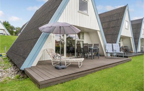 a house with a deck with an umbrella and chairs at Two-Bedroom Holiday Home In Knebel in Knebel