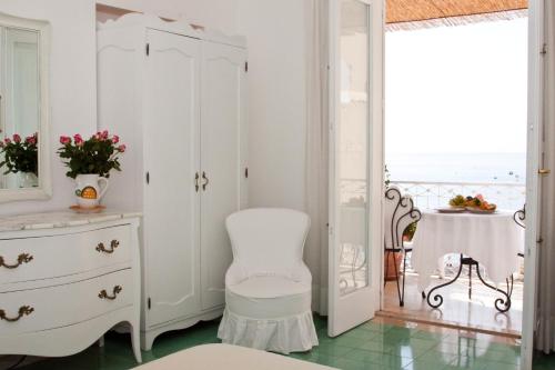 Cette chambre blanche dispose d'une chaise et d'une commode. dans l'établissement Villa La Tartana, à Positano