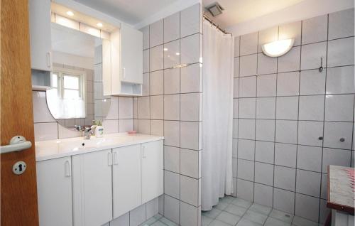 a white bathroom with a sink and a mirror at Nice Home In Hvide Sande With House A Panoramic View in Havrvig