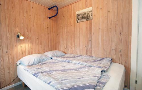 a bed in a room with a wooden wall at Nice Home In Hvide Sande With House A Panoramic View in Havrvig