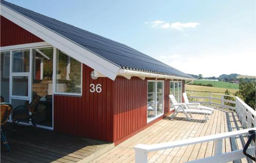 a red house with a deck with two chairs on it at Amazing Home In Knebel With Sauna in Skødshoved Strand