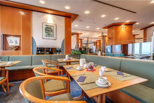 ケムニッツにあるCongress Hotel Chemnitzの木製のテーブルと椅子が備わるレストラン
