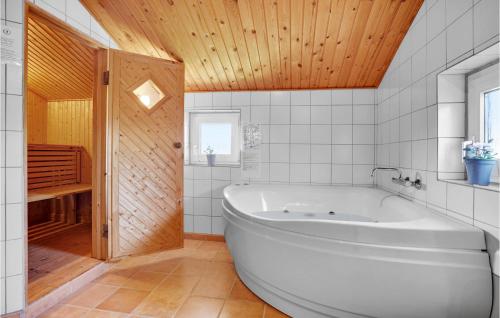 BjerregårdにあるNice Home In Hvide Sande With Wifiの木製の天井のバスルーム(白いバスタブ付)