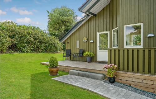 a green house with a porch with chairs on it at 3 Bedroom Beautiful Home In Hejls in Hejls