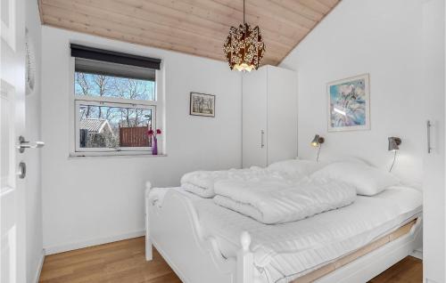 a white bedroom with a white bed with a chandelier at Beautiful Home In Storvorde With Sauna in Storvorde