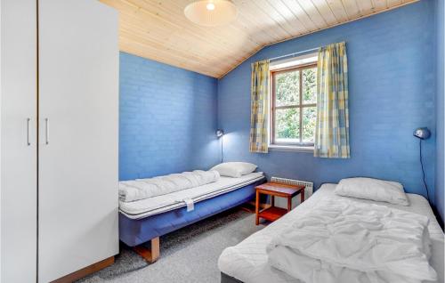 a blue room with two beds and a window at Stunning Home In Rm With 5 Bedrooms, Sauna And Wifi in Bolilmark