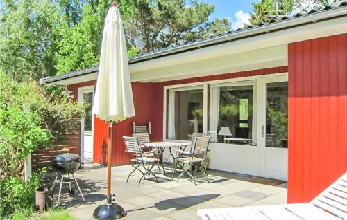 eine Terrasse mit Tisch und Stühlen und einem Sonnenschirm in der Unterkunft Awesome Home In Aakirkeby With Kitchen in Vester Sømarken