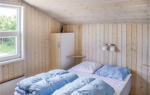 Amazing Home In Storvorde With Wifi في Egense: غرفة نوم بسرير مع مخدات زرقاء وثلاجة