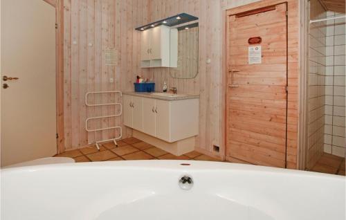 y baño con bañera, lavabo y espejo. en Beautiful Home In Sklskr With 4 Bedrooms, Sauna And Wifi, en Skælskør