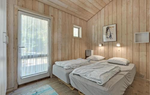 2 camas en una habitación con paredes de madera y ventana en Awesome Home In Vggerlse With Kitchen, en Bøtø By