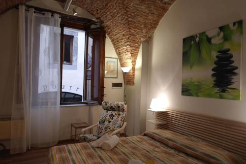 ルッカにあるYOURHOMEINLUCCA Le Volteのベッドルーム1室(ベッド1台、椅子、窓付)