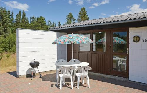 un patio con un tavolo, due sedie e un ombrellone di Holiday Home Fyrrekrogen Nørre Nebel Iii a Lønne Hede