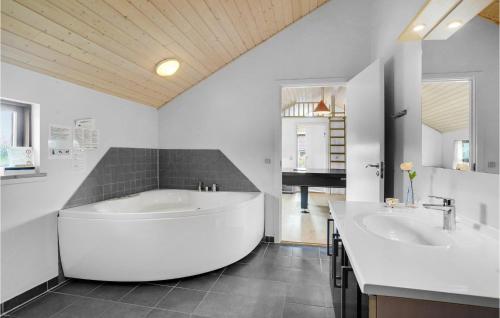 4 Bedroom Amazing Home In Otterup في Otterup: حمام كبير مع مغسلتين وحوض استحمام كبير