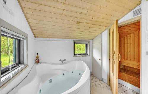 BjerregårdにあるBeautiful Home In Hvide Sande With Wifiの木製の天井のバスルーム(白いバスタブ付)