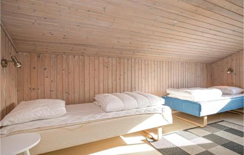 two beds in a room with wooden walls at Cozy Home In Hjrring With House Sea View in Lønstrup