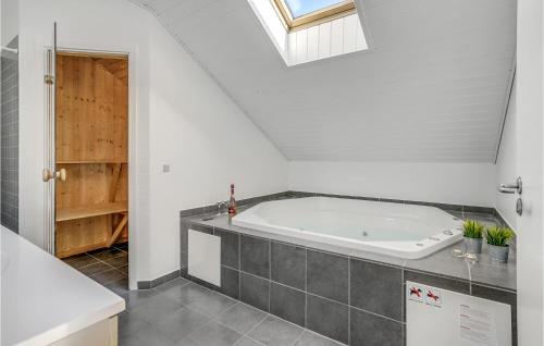a bath tub in a bathroom with a skylight at Awesome Home In Otterup With Sauna in Hasmark