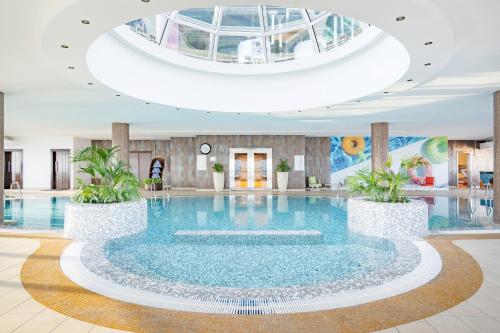 Qabila Westbay Hotel by Marriott في الدوحة: مسبح كبير في لوبي الفندق بسقف ثابت