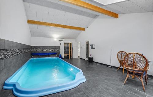 a swimming pool in a room with chairs and a table at Amazing Home In Rødby With Sauna in Rødby
