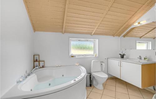 a white bathroom with a tub and a toilet at Stunning Home In Rm With 3 Bedrooms, Sauna And Wifi in Rømø Kirkeby