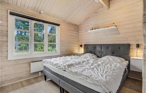 Bett in einem Zimmer mit Holzwänden und Fenstern in der Unterkunft Stunning Home In Glesborg With Wifi in Glesborg