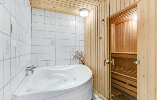baño con bañera blanca y paredes de madera en Pet Friendly Home In Christiansfeld With Sauna en Christiansfeld