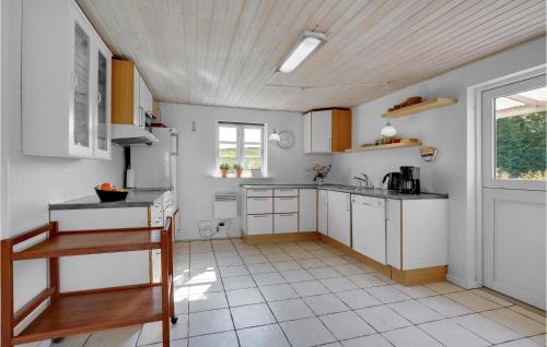 a kitchen with white cabinets and a table and a window at Beautiful Home In Christiansfeld in Christiansfeld