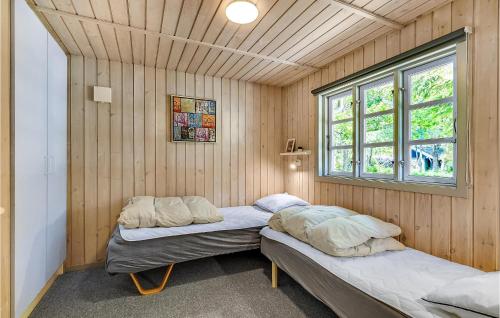 2 camas en una habitación con paredes de madera y ventana en Pet Friendly Home In Ansager With Kitchen en Ansager