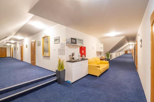 a hallway in a hospital with a yellow chair and a room at Hotel Belcredi in Brno