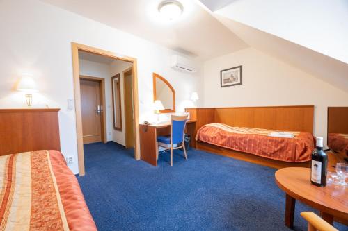 a hotel room with two beds and a desk at Hotel Belcredi in Brno