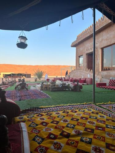 a house in the middle of the desert with a colorful carpet at Safari Desert Camp in Shāhiq