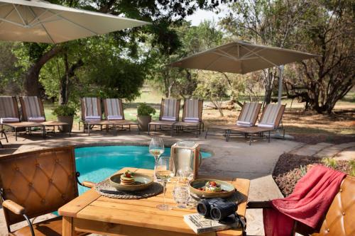 a table with wine glasses on it next to a pool at Kwafubesi Tented Safari Camp in Mabula