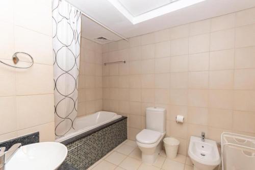 a bathroom with a toilet and a tub and a sink at Spacious 3 Bed Room Apartment - Palm Jumeirah Dubai in Dubai