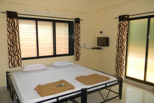 a bed in a room with two windows at Suma beach resort in Dapoli
