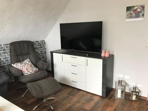 a living room with a flat screen tv and a chair at Haus Eierhof in Papenburg