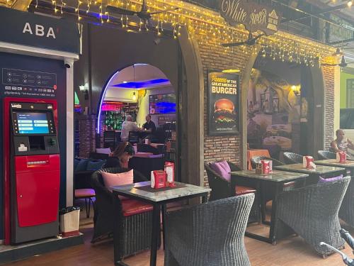 a restaurant with tables and chairs and a red soda machine at White River guesthouse in Phnom Penh