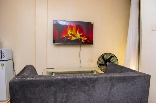 a living room with a couch and a tv on the wall at Unique, Stylish Studio Apartment in Kisumu
