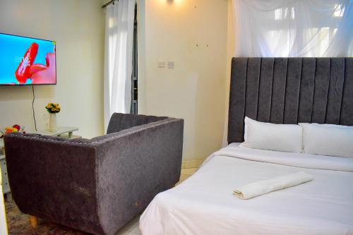 a hotel room with a bed and a chair at Unique, Stylish Studio Apartment in Kisumu