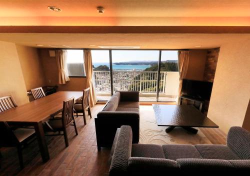 a living room with a couch and a table and chairs at Katsuura Hilltop Hotel & Residence in Katsuura