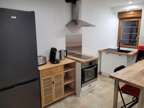 a kitchen with a black refrigerator and a table at maison des vendangeurs in Villarzel-Cabardès