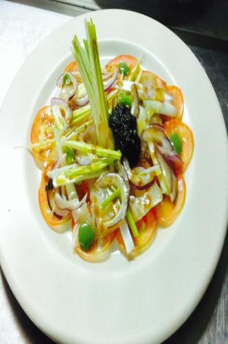 a white plate of food with vegetables on a table at Hostal León in Trujillo
