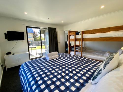 a bedroom with a bed and a bunk bed and a television at Townhouse Feel in Irishman in Twizel