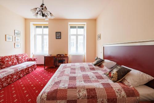 Altwienerhof Aparthotel في فيينا: غرفة نوم بسرير واريكة